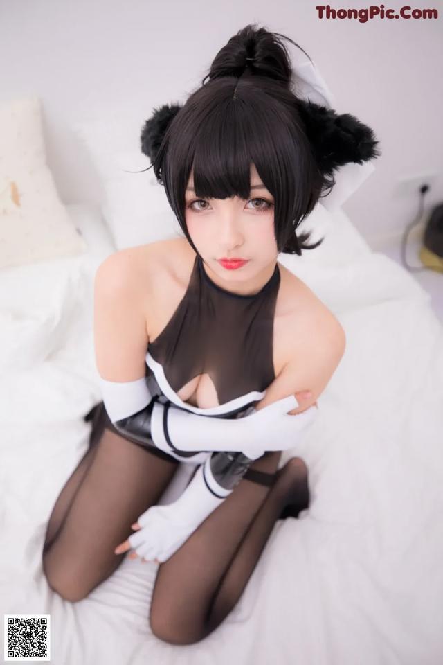 A woman in a black and white outfit sitting on a bed.