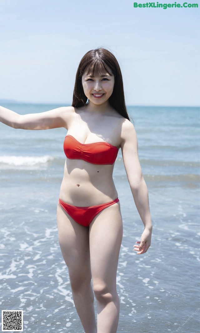 A woman in a red bikini standing in the ocean.