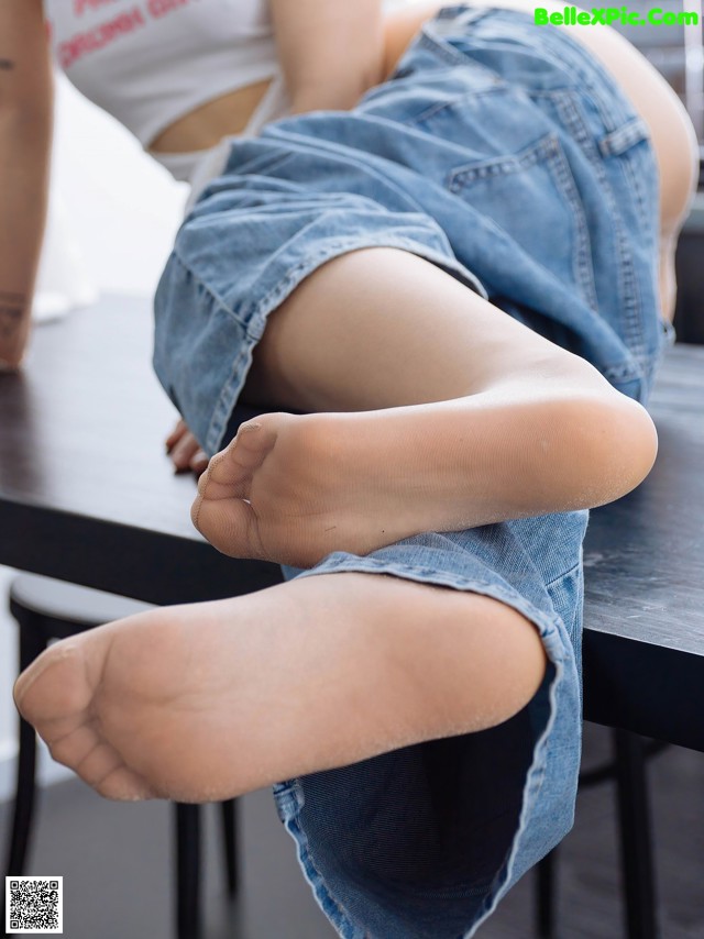 A woman sitting on top of a table with her feet up.