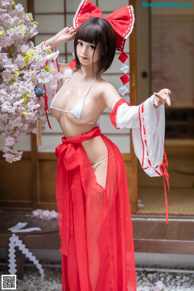 A woman in a red and white kimono posing for a picture.