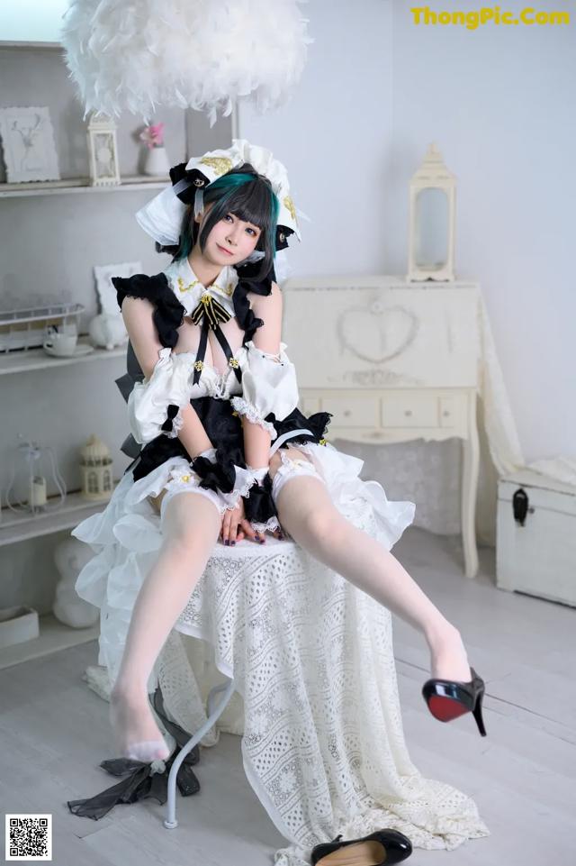 A woman in a maid outfit sitting on a chair.