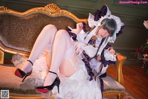 A woman in a maid outfit sitting on a couch.