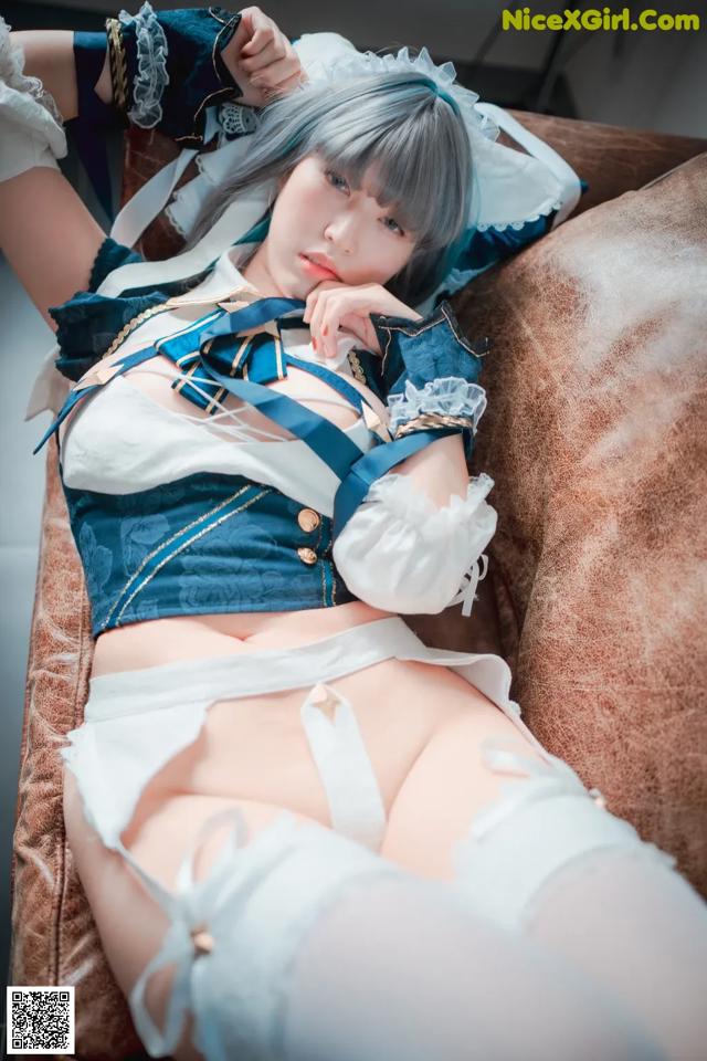 A woman in a blue and white outfit laying on a couch.