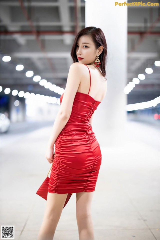 A woman in a red dress is posing for a picture.