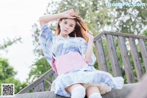 A woman in a blue and pink kimono standing in the grass.