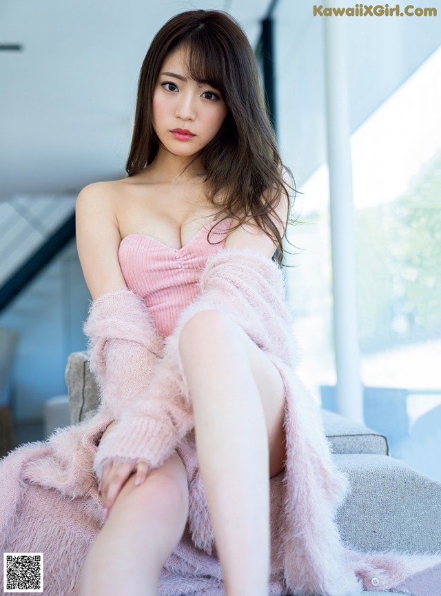 A woman in a pink dress sitting on a couch.