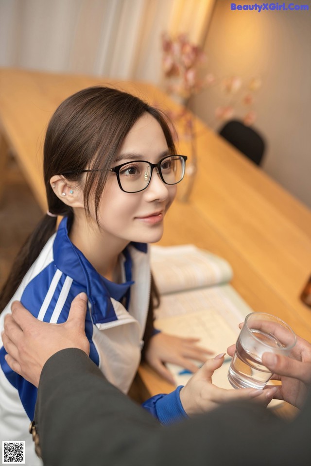 A woman sitting at a table with a glass of water.