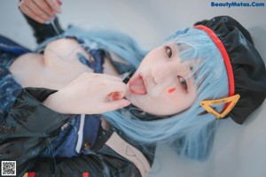 A woman with blue hair wearing a black hat.
