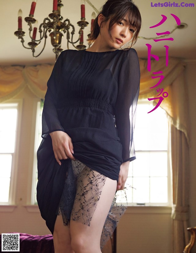 A woman in a black dress is posing for a picture.