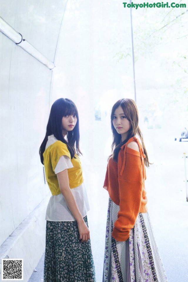 Two young women standing next to each other in a room.