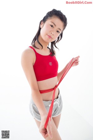 A woman in a red sports bra top and gray shorts.