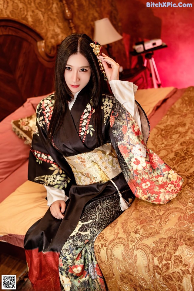 A woman in a kimono sitting on a bed.