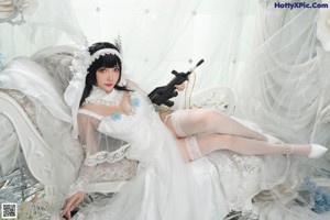 A woman in a wedding dress sitting on a bed.