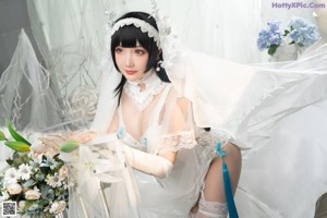 A woman in a wedding dress sitting on a bed.