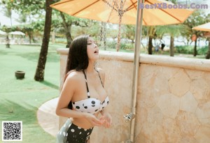 A woman in a white bikini sitting on the beach.