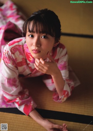 A woman in a kimono holding a pink pinwheel.