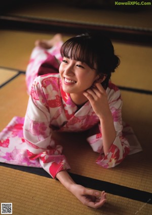 A woman in a pink kimono sitting by a window.