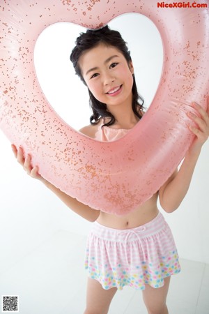 A young woman leaning against a white wall.