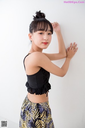 A woman standing on a scale wearing a black top and shorts.