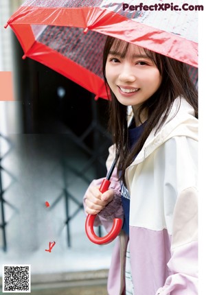 A woman holding a red umbrella in front of a white background.