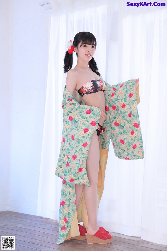 A woman in a bikini and a kimono posing for a picture.