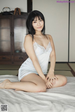 A woman in a white lingerie posing on a bed.