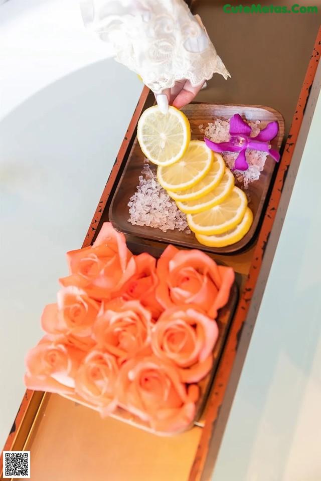 A tray of flowers and lemons on top of a bathtub.