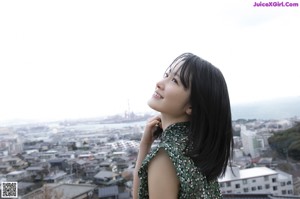 A woman in a green dress looking out over a city.