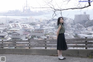 A woman in a green dress sitting on a railing.