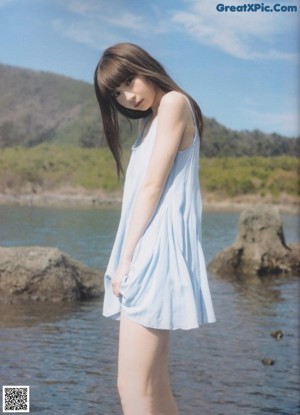 A woman with long brown hair wearing a blue tank top.