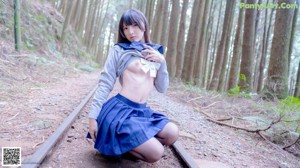 A woman in black stockings and a blue jacket is posing for the camera.