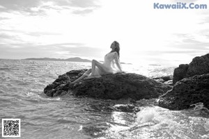 A woman sitting on a wooden bench on the beach.