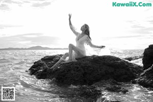 A woman in a bikini leaning against a wall next to a pool.