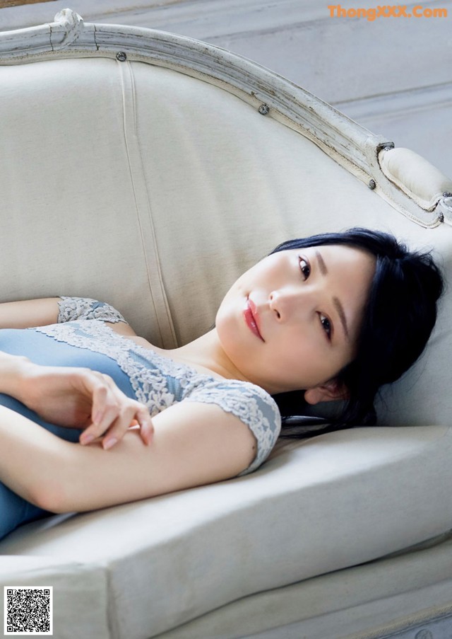 A woman laying on top of a white couch.