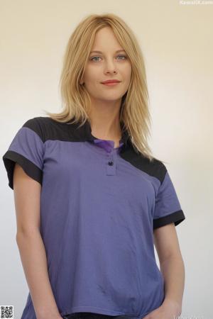 A woman in a blue and pink bra sitting on a bed.