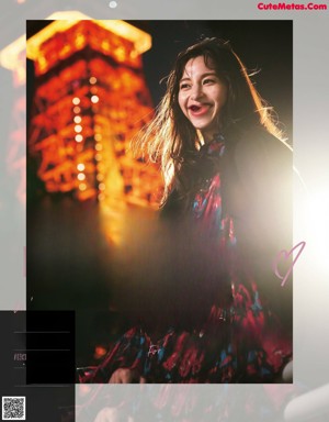 A woman standing in front of the Eiffel Tower at night.