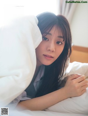 A woman sitting on top of a bed in a blue shirt.