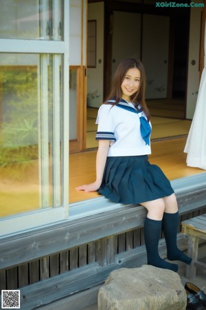 A woman in a sailor outfit crouching on the floor.