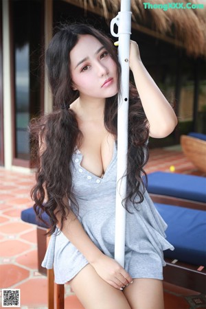A woman in a gray shirt is holding a lollipop.