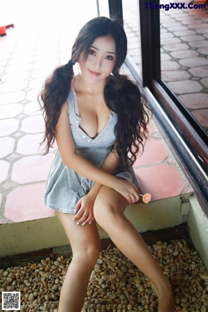 A woman in a gray dress sitting on a chair.
