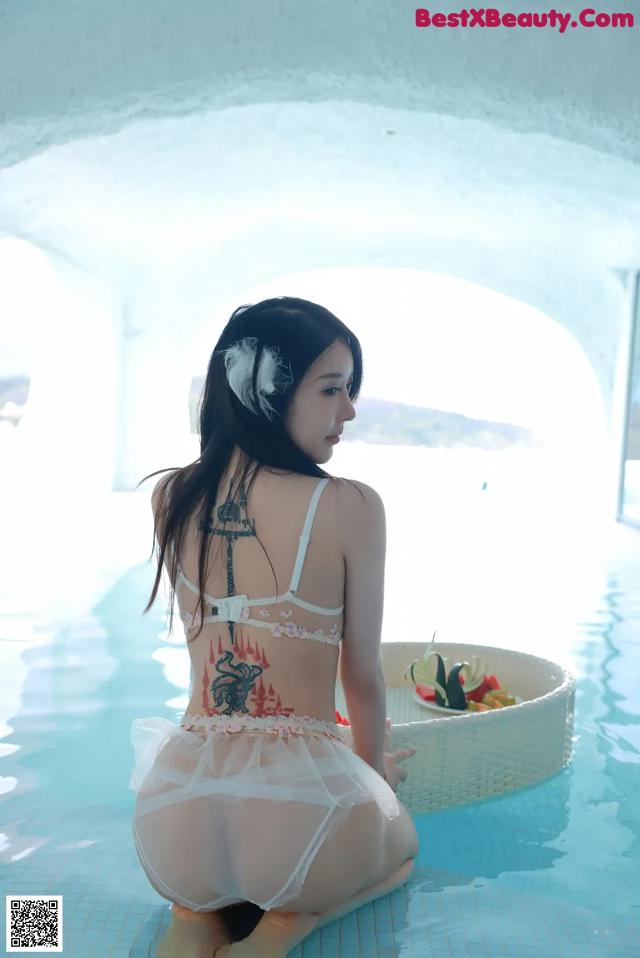 A woman in a white lingerie sitting in a pool.