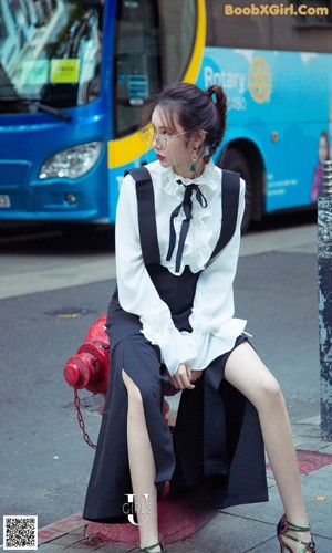 a woman sitting on the ground next to a fence