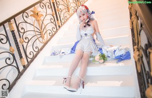 A woman in a white and blue outfit sitting on a white couch.