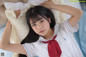 A woman in a school uniform sitting on the floor.