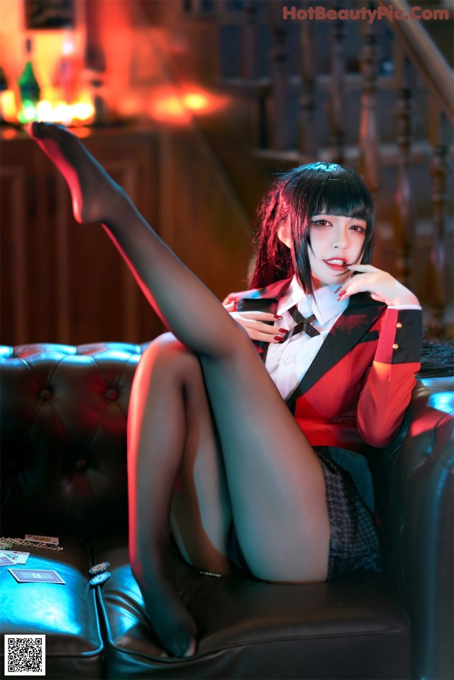 A woman sitting on top of a black leather couch.