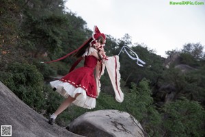 A woman in a red and white dress holding a stick.