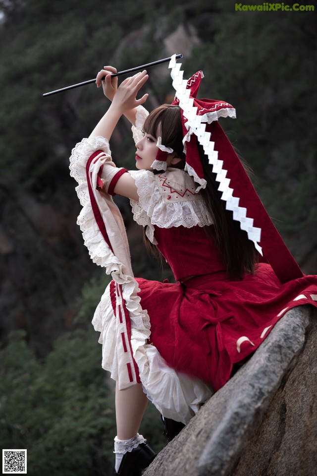 A woman in a red and white dress holding a stick.