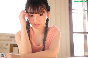 A young girl standing in a room with a wooden floor.