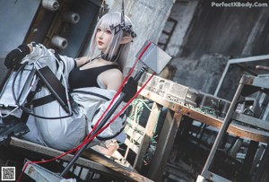 A woman in a black top and white pants standing in an abandoned building.