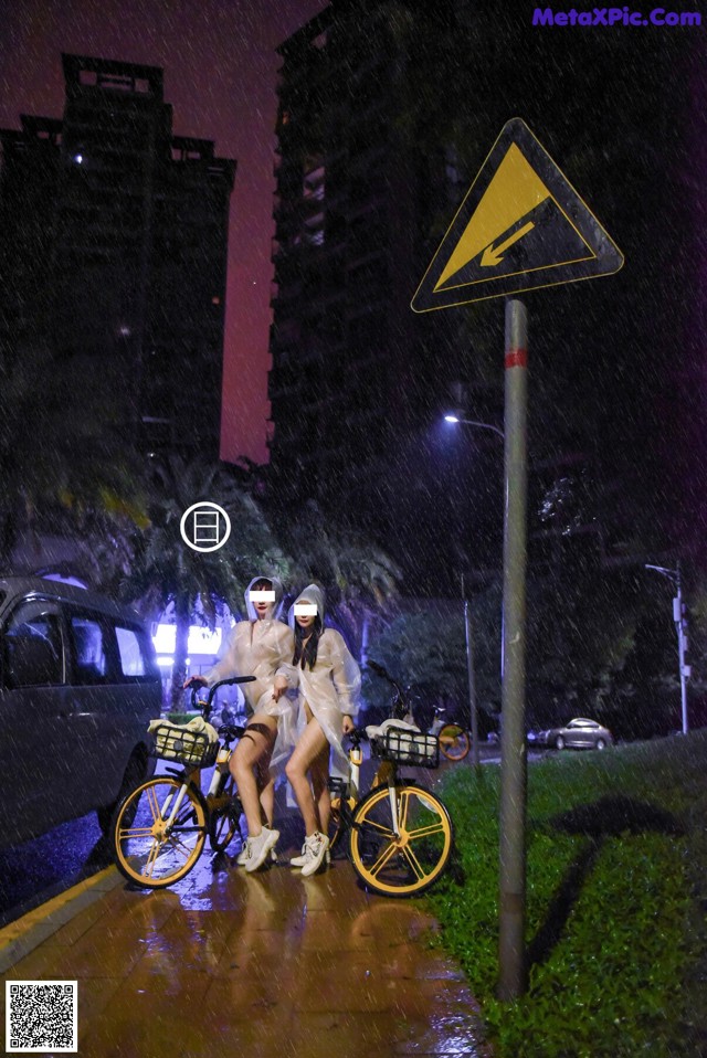 A couple of people riding bikes down a street at night.